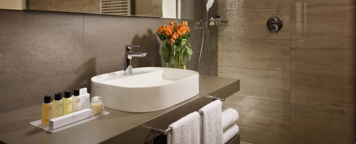 Baño de hotel con toallas blancas y acabados de piedra
