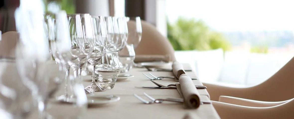 Mantelería blanca y cristalería en una mesa preparada para recibir